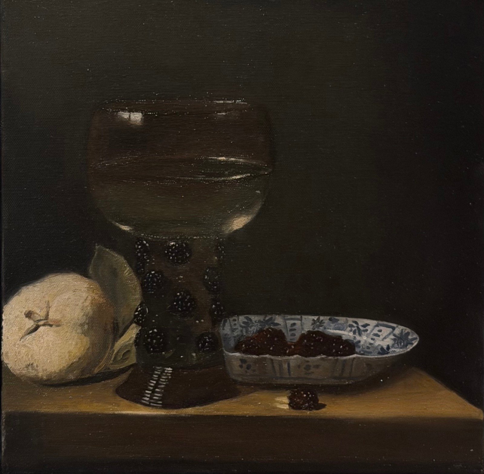 Dark still life of a roemer goblet, a pale quince with its leaf, and a blue-and-white porcelain dish of berries on a wooden ledge